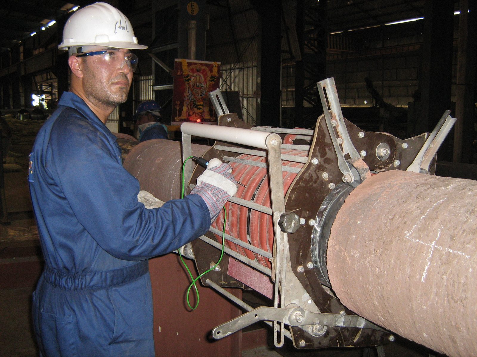 Ehab Abutahoun setting up an induction heating coil on a pipe joint in a fabrication yard
