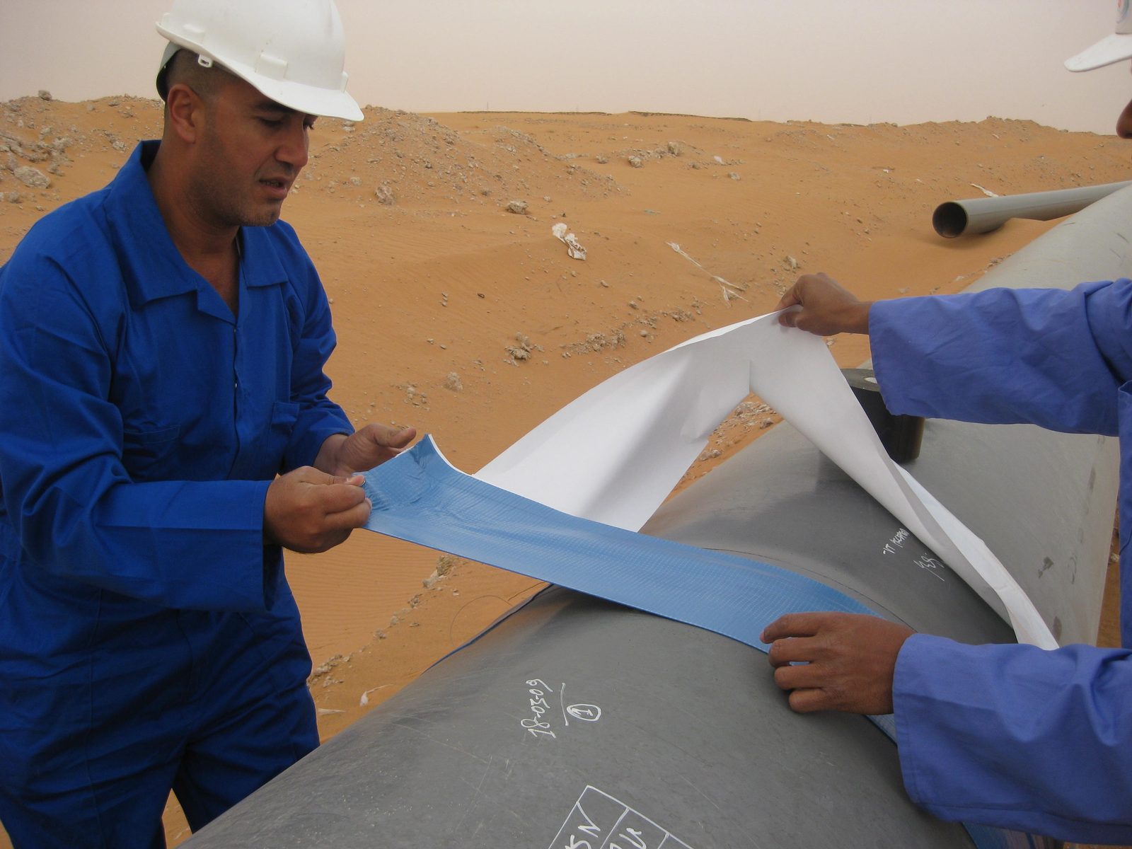 Ehab Abutahoun applying field joint coating material to a buried pipeline in the desert